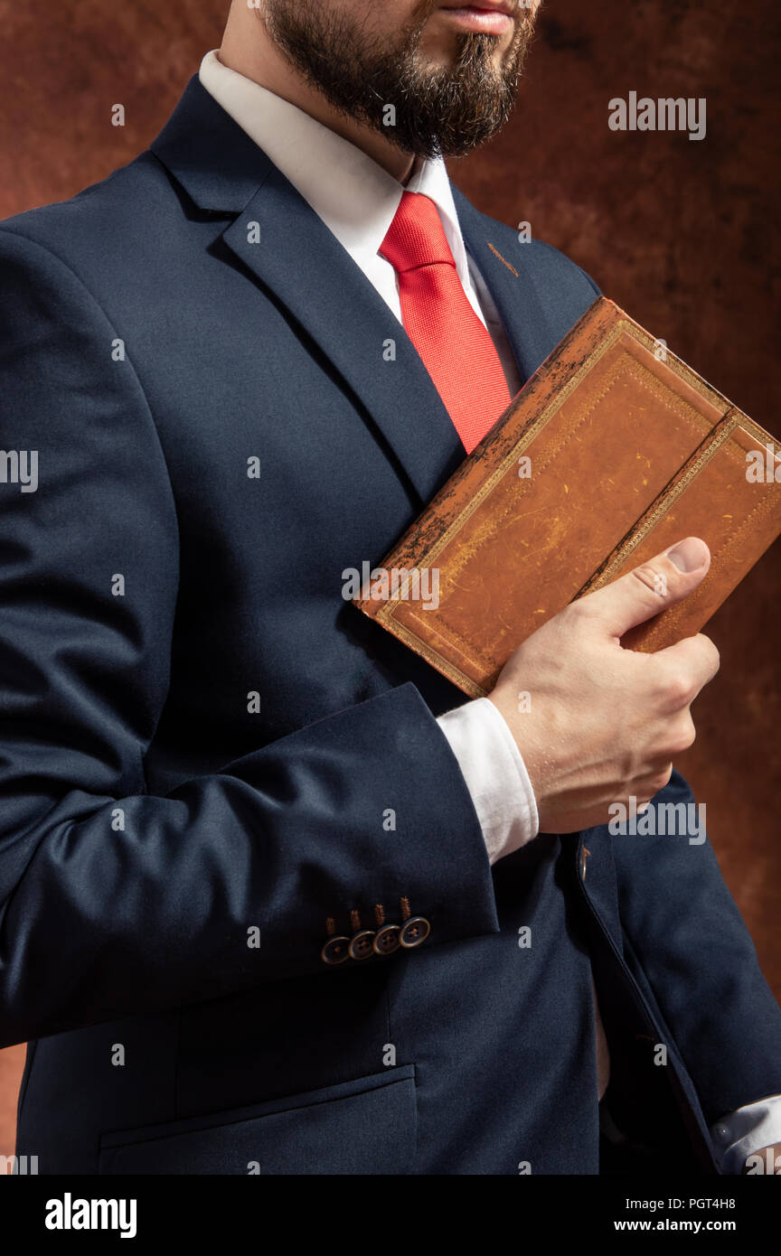Man in suit stands with old vintage book Stock Photo