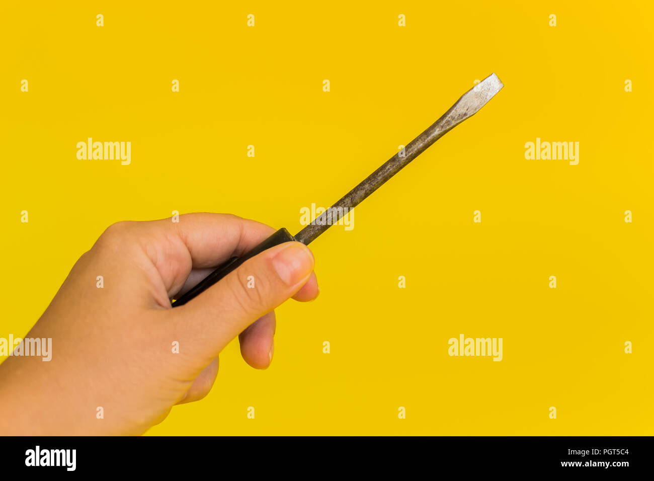 hand holding a screwdriver on a yellow background Stock Photo
