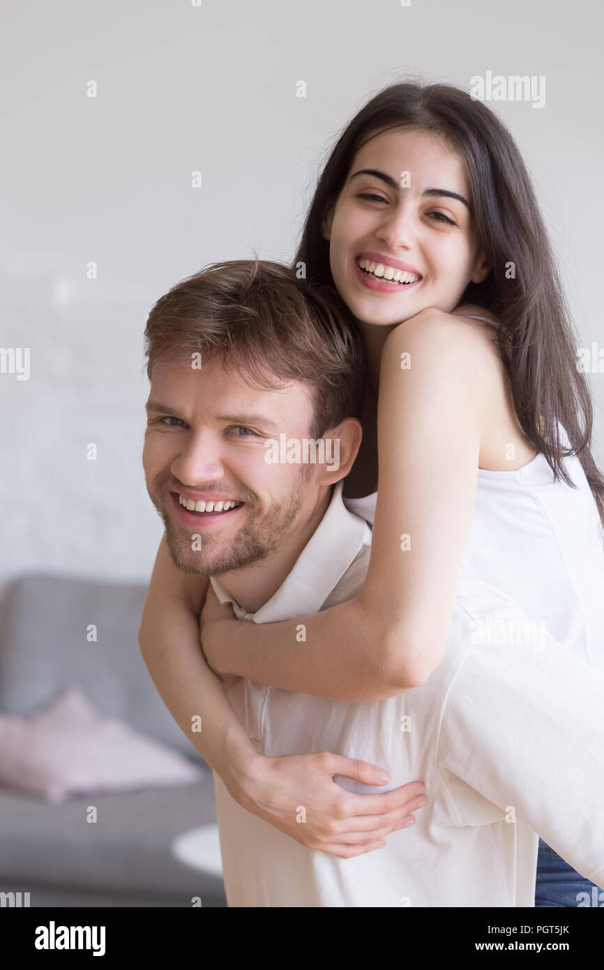Happy young girlfriend piggyback smiling boyfriend having fun at Stock Photo