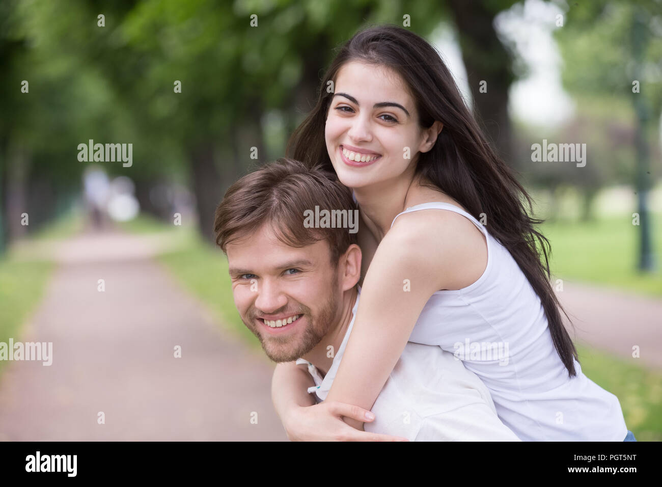 Portrait of smiling young girlfriend piggyback millennial boyfri Stock Photo