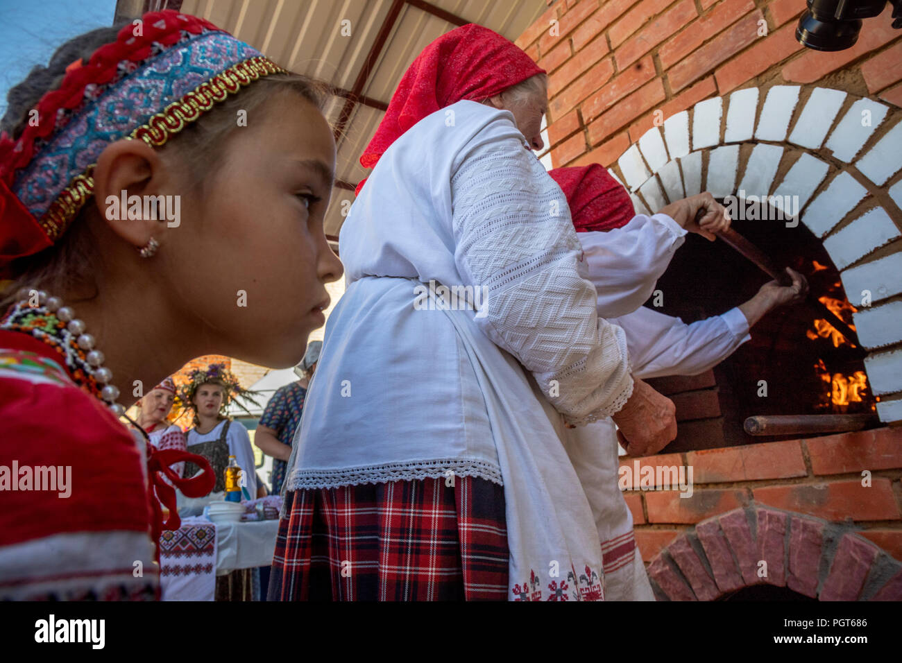 A girl watches baked pancakes in an oven according to old Russian tradition in village of Tambov region, Russia Stock Photo