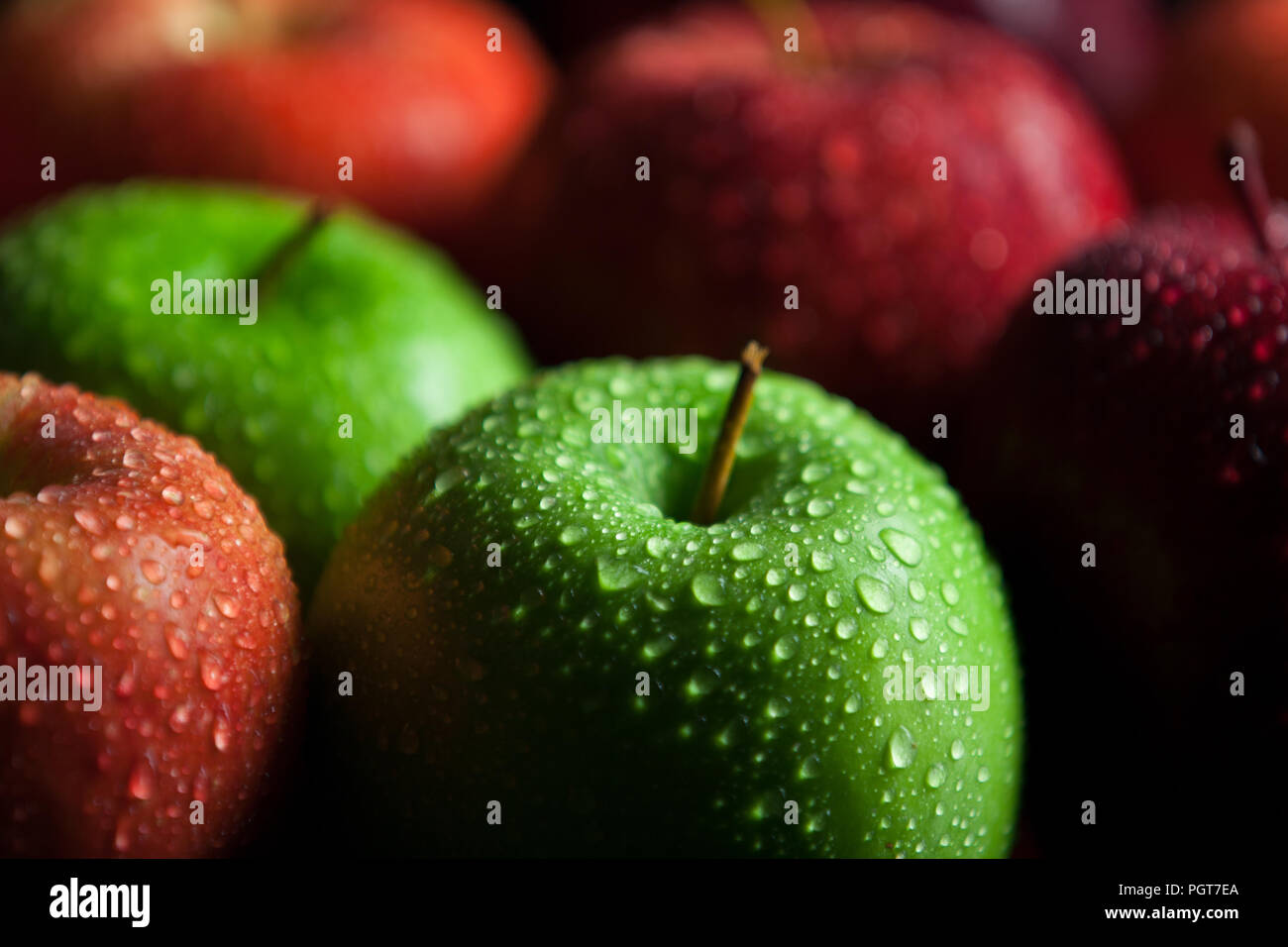 Granny smith and red delicious apples with water droplets and dark shadows Stock Photo