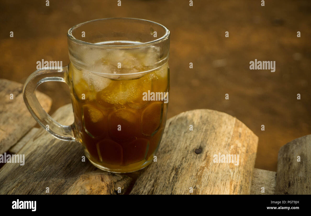 glass of ice tamarind tea asem jawa liquid on wooden table in central java Stock Photo