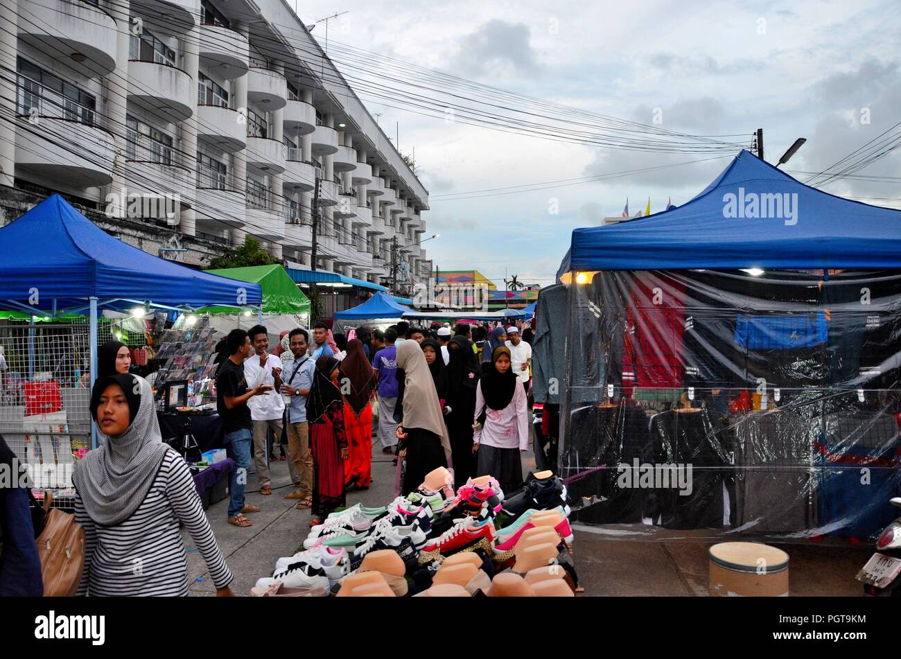 Crowds of people hang around outdoor street market shops & food stalls