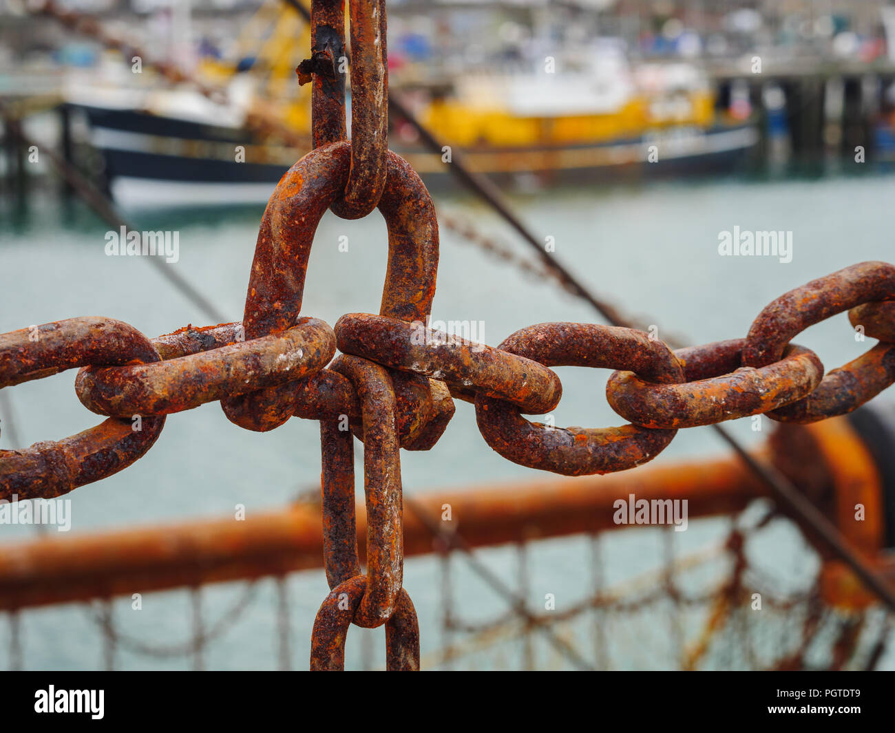 Rusted metal chains of the fishing nets of a fishing trawler boat moored in Newlyn harbour. In Newlyn, Cornwall, England. Stock Photo