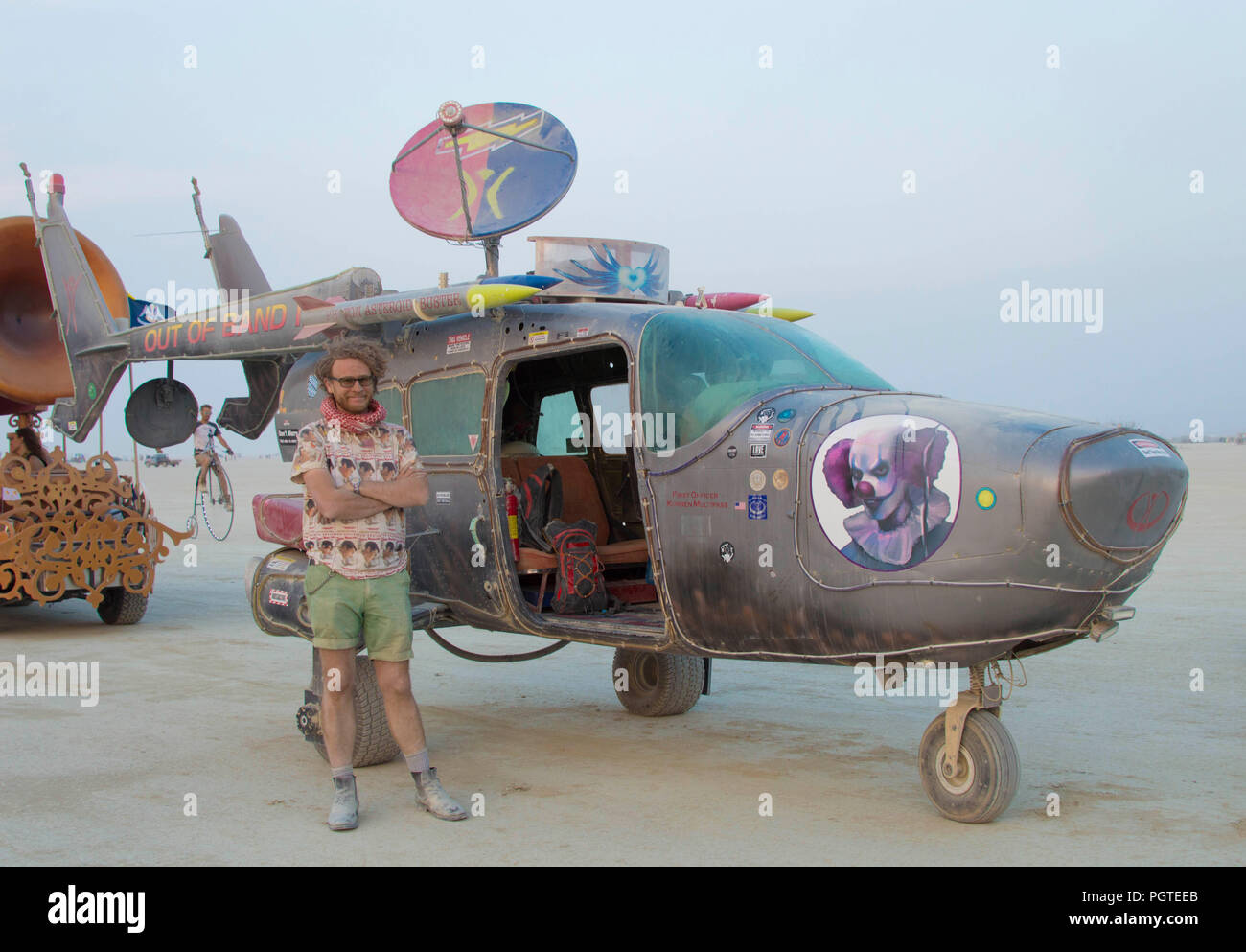 A burner poses next to his art car on the playa during the annual Burning Man counter culture festival in the desert August 25, 2018 near Black Rock, Nevada. Each year 80,000 of people set up a temporary art city in the middle of the desert. Stock Photo