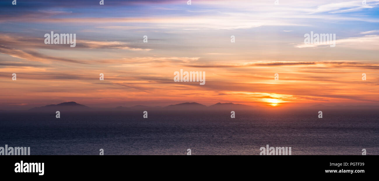 Looking out across the sea to the Western Isles off the coast of Scotland at sunset Stock Photo