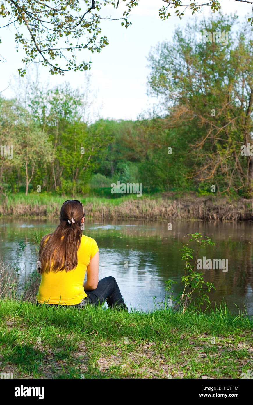 girl sitting on the bank of the river Stock Photo - Alamy
