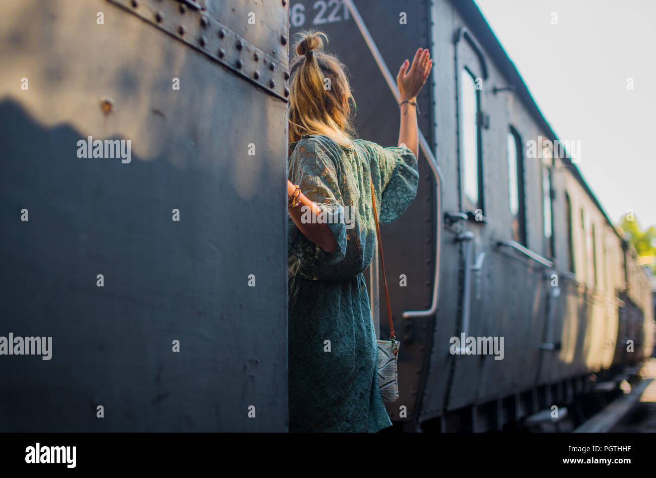 A girl getting on a train and waving goodbye Stock Photo
