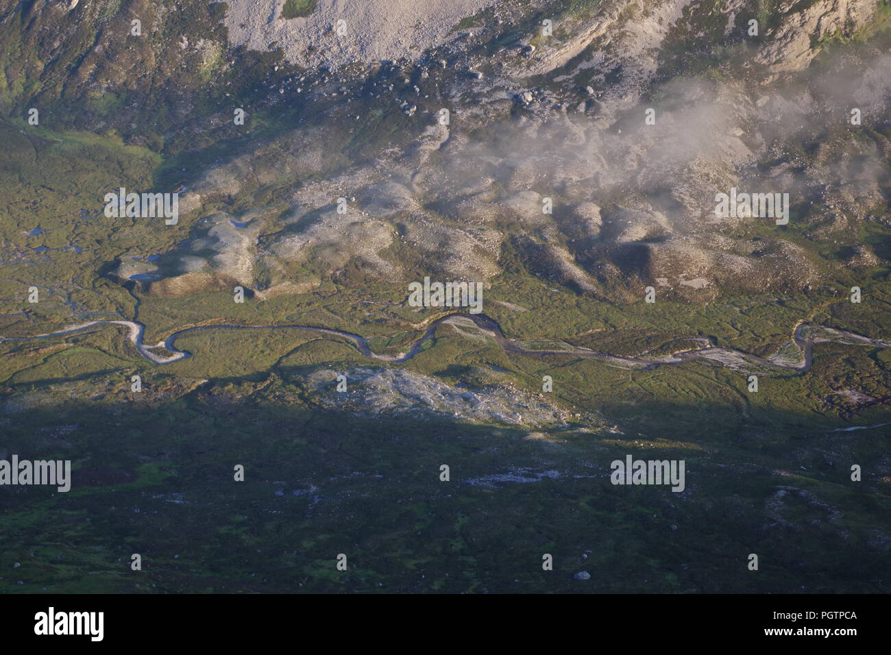 Meandering Burn Stream along the Valley Floor Under Slight Cloud Inversion. Birds Eye View from Meall a'Ghiubhais Mountain. Kinlochewe, Torridon, UK. Stock Photo