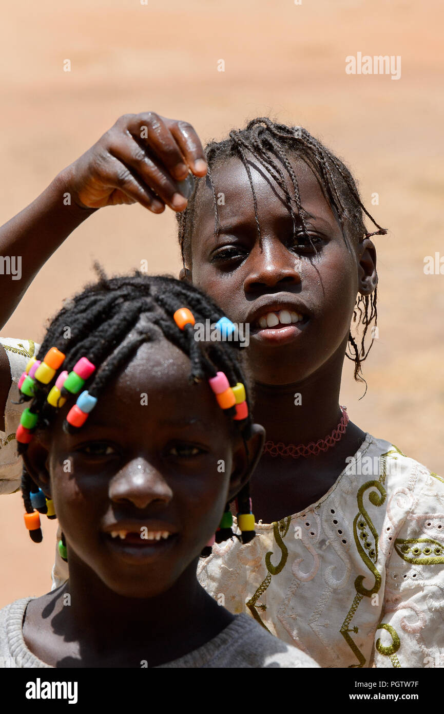 CANCHUNGO, GUINEA BISSAU - MAY 3, 2017: Unidentified local little girls with braids smile. Bissau-Guinean people suffer of poverty due to the bad econ Stock Photo