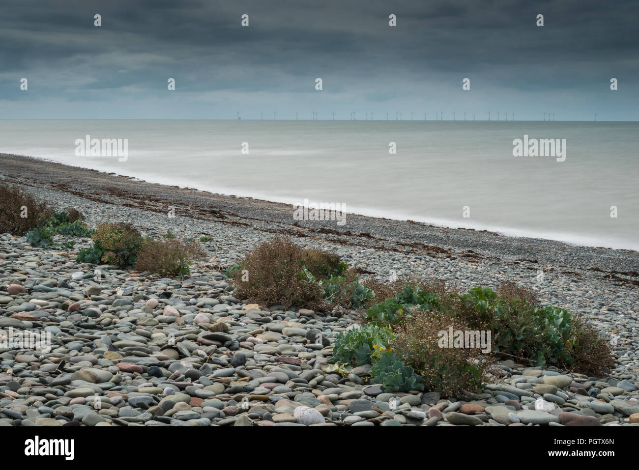 The deserted western shoreline and beach of Walney Island off the Cumbrian coast in summer with long exposure on the sea and shingle beach. Stock Photo