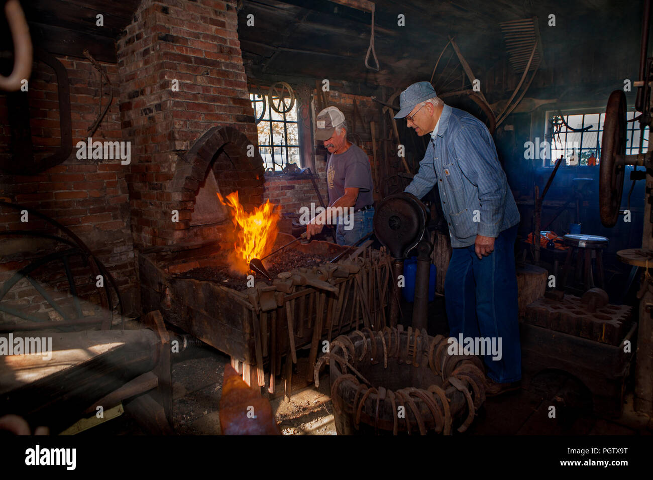 Two blacksmiths working at a forge in the blacksmith shop in Peacham ...