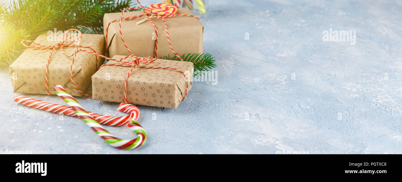 Gift boxes in kraft paper, candy canes and branch of Christmas trees on ...