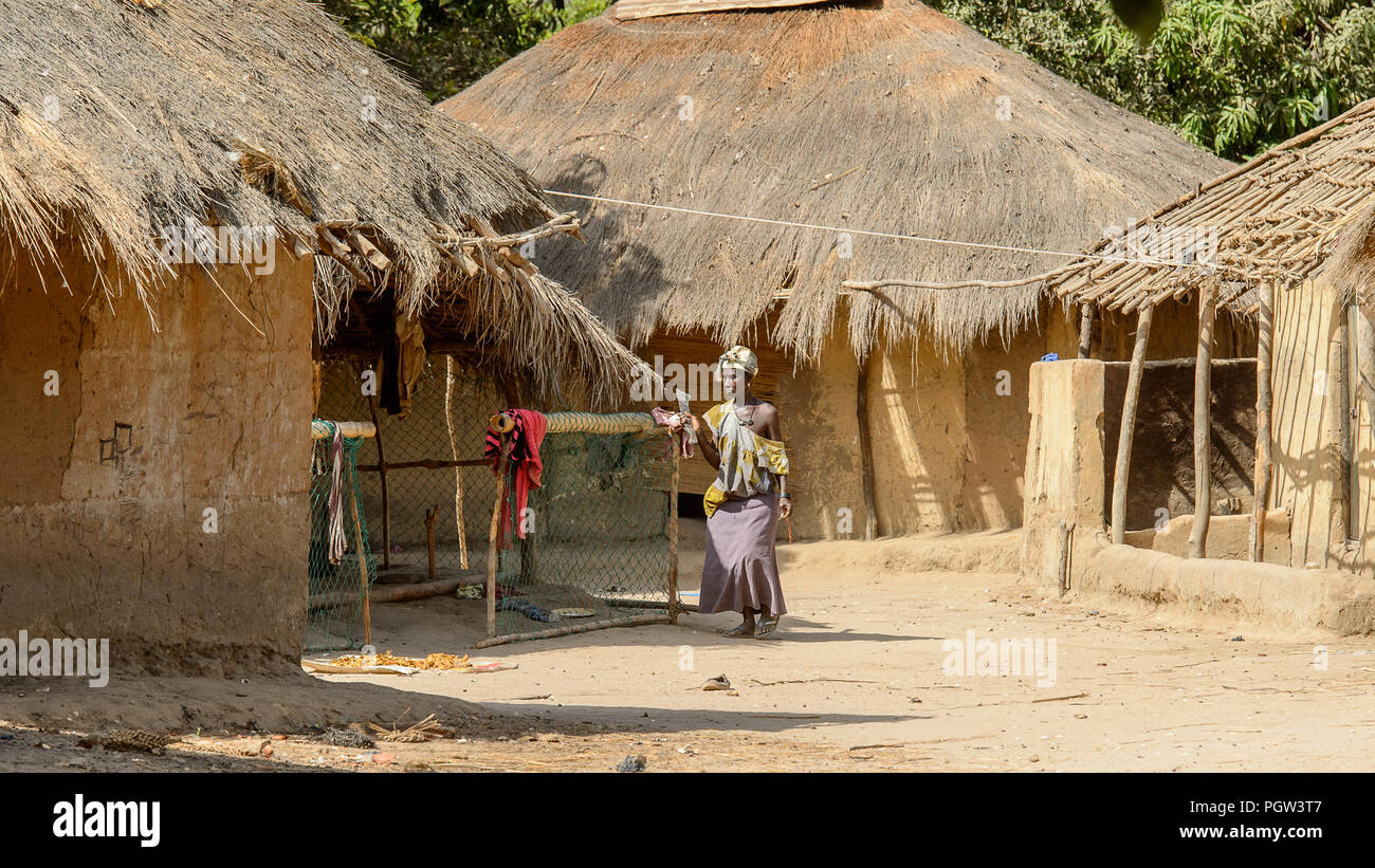 CANHABAQUE, GUINEA BISSAU - MAY 4, 2017: Unidentified local woman in traditional clothes walks with machete in a village of the Canhabaque island. Peo Stock Photo