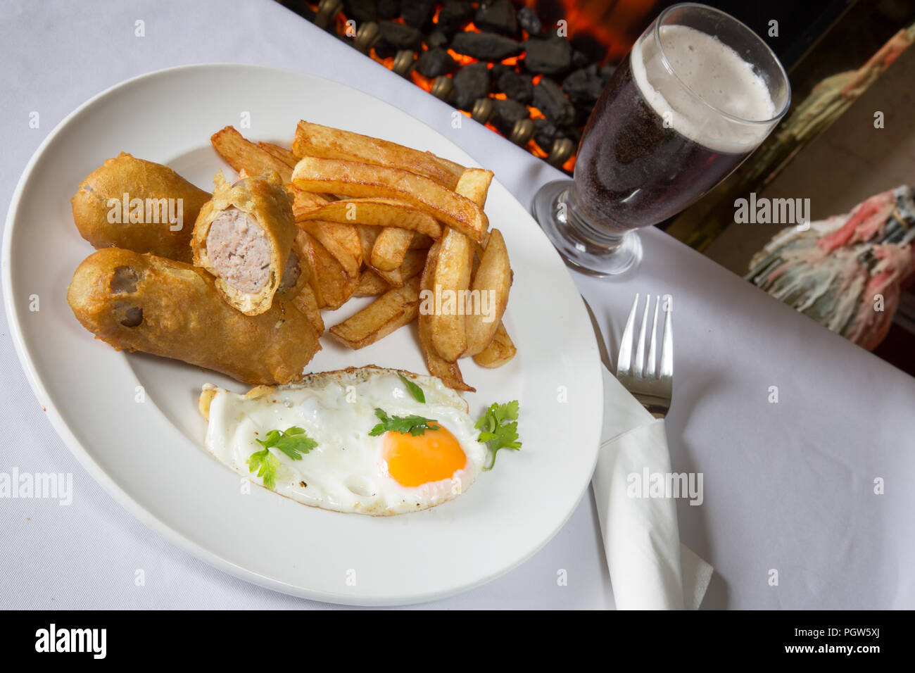 Traditional English supper of deep fried battered sausage with chips/fries and a fried egg Stock Photo