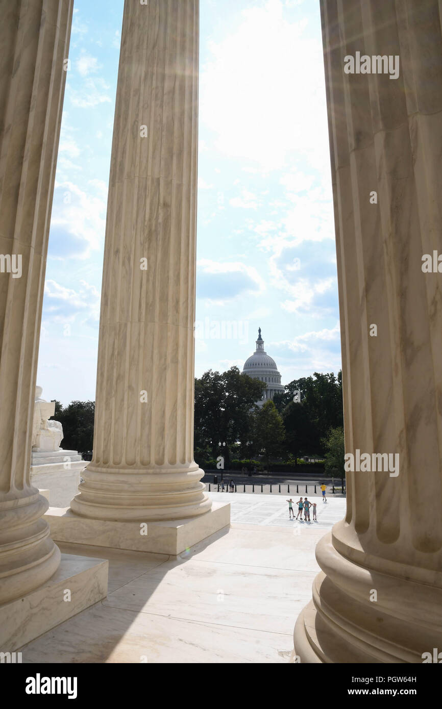 Columns of the U.S. Supreme Court building with the U.S. Capitol in the background. Stock Photo