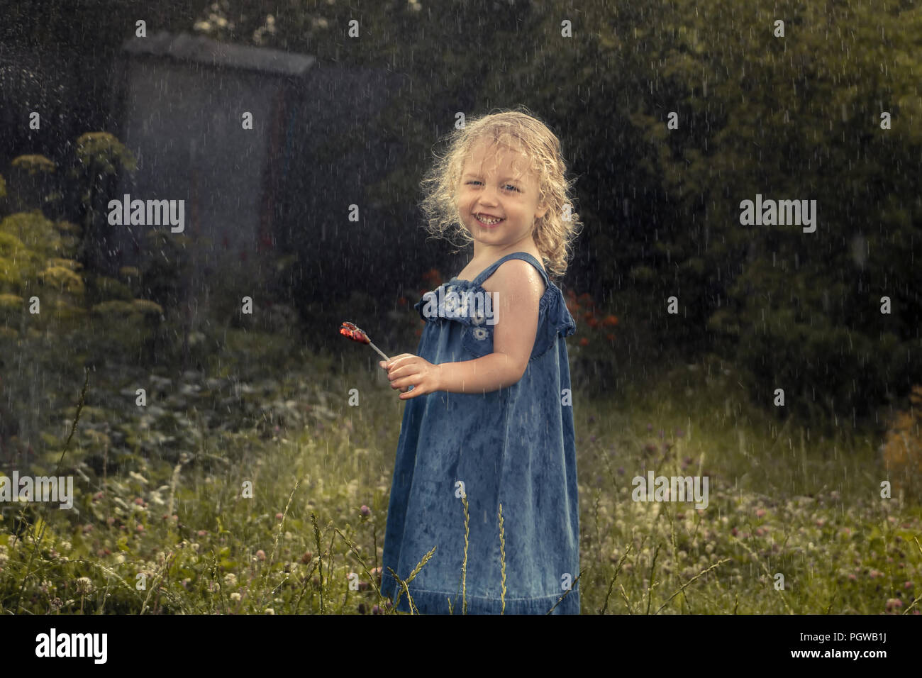 Happy cheerful child girl smiling under rain countryside concept happy carefree childhood in countryside Stock Photo