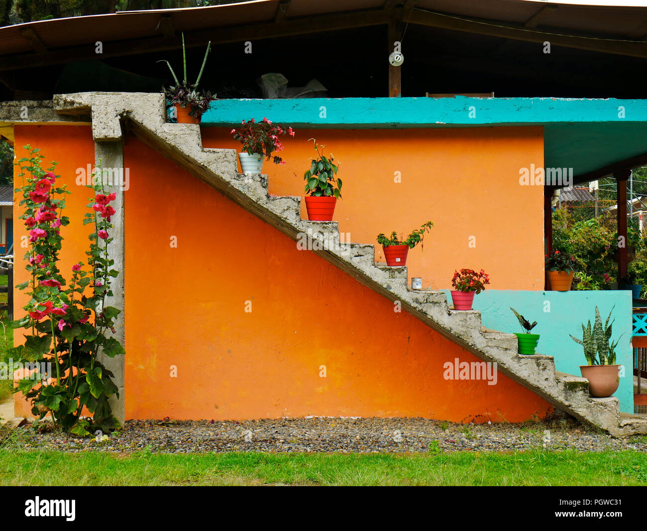 concrete wall painted in orange and ligh blue with a stair filled with pots placed every other step country house Stock Photo