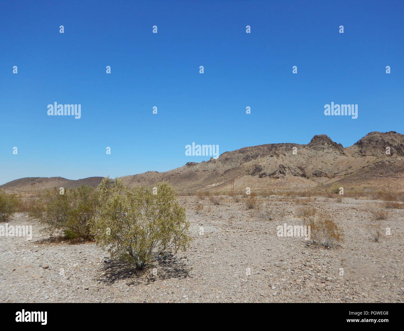 Barren desert landscape with rocky barren desert mountains under blue sky. Stock Photo