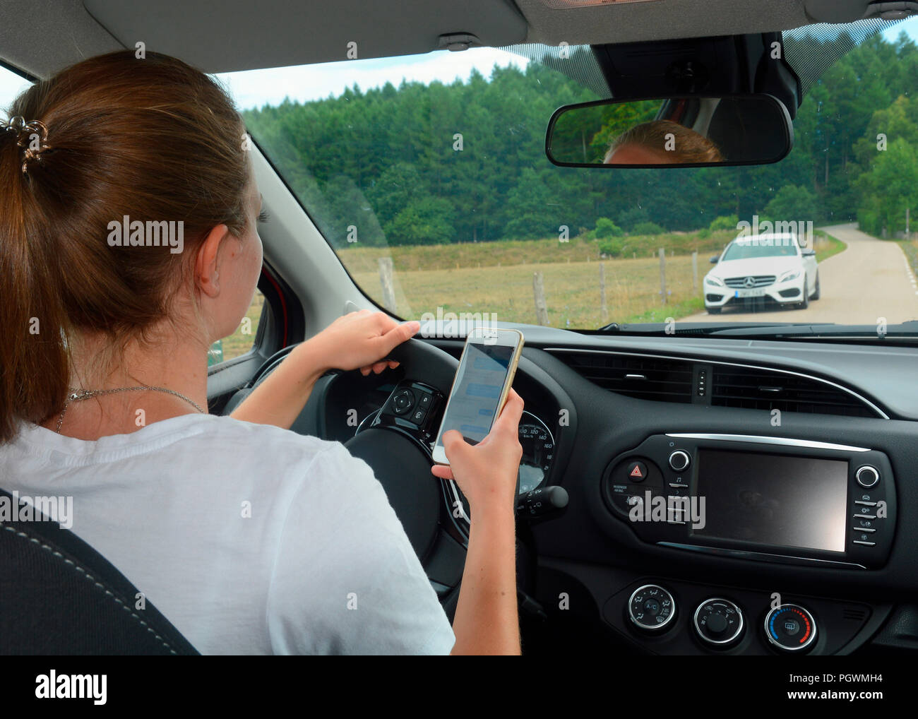 Young woman using a mobil phone while she drive a car, Sweden Stock Photo