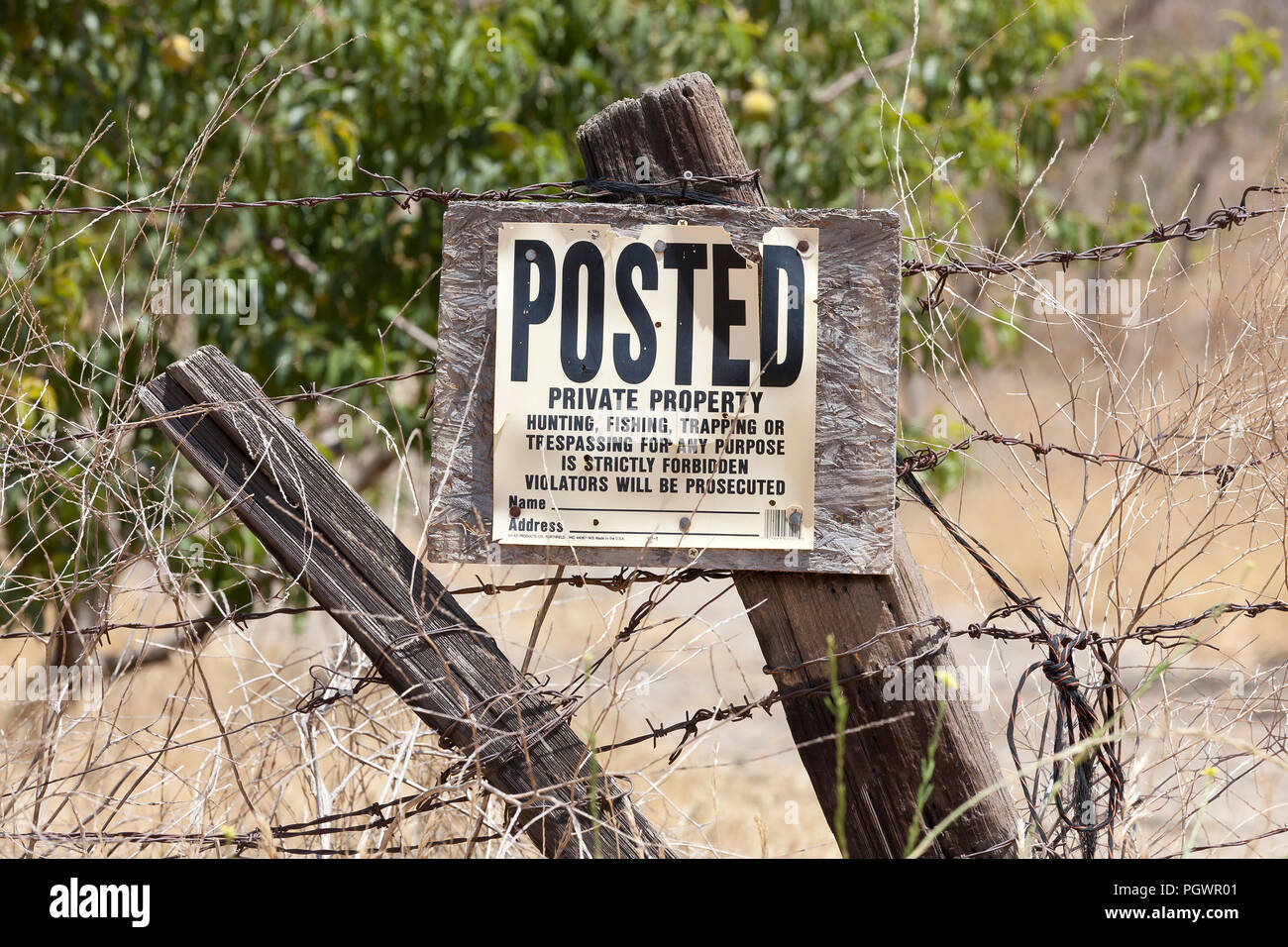 No trespassing, No hunting, No fishing, No trapping sign on fence post on rural private property - California USA Stock Photo