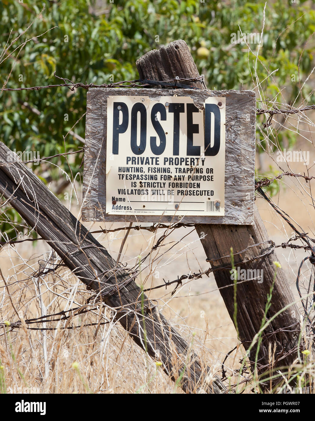 No trespassing, No hunting, No fishing, No trapping sign on fence post on rural private property - California USA Stock Photo