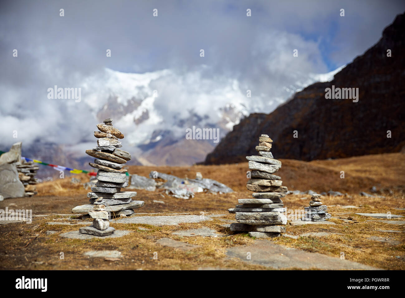 Small piles from stones on the Mardi Himal trek and cloudy peaks of Himalaya Mountains in Nepal Stock Photo