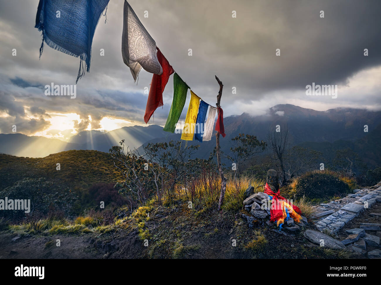 Small piles from stones and Tibetan prayer flags Lung Ta at the Mardi Himal Base Camp at cloudy sunset peaks of Himalaya Mountains in Nepal Stock Photo