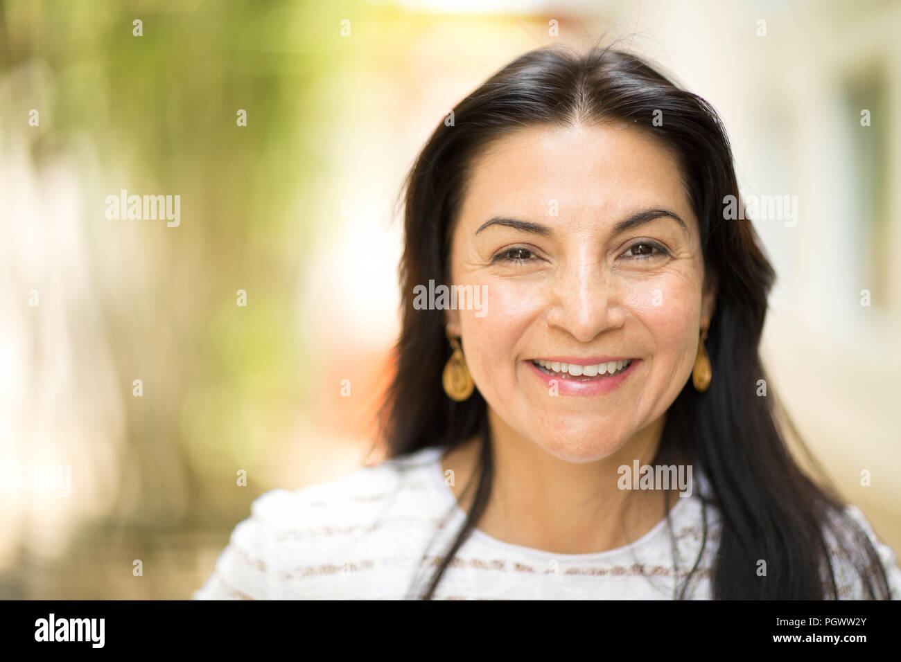 Happy Hispnaic woman smiling and standing outside. Stock Photo
