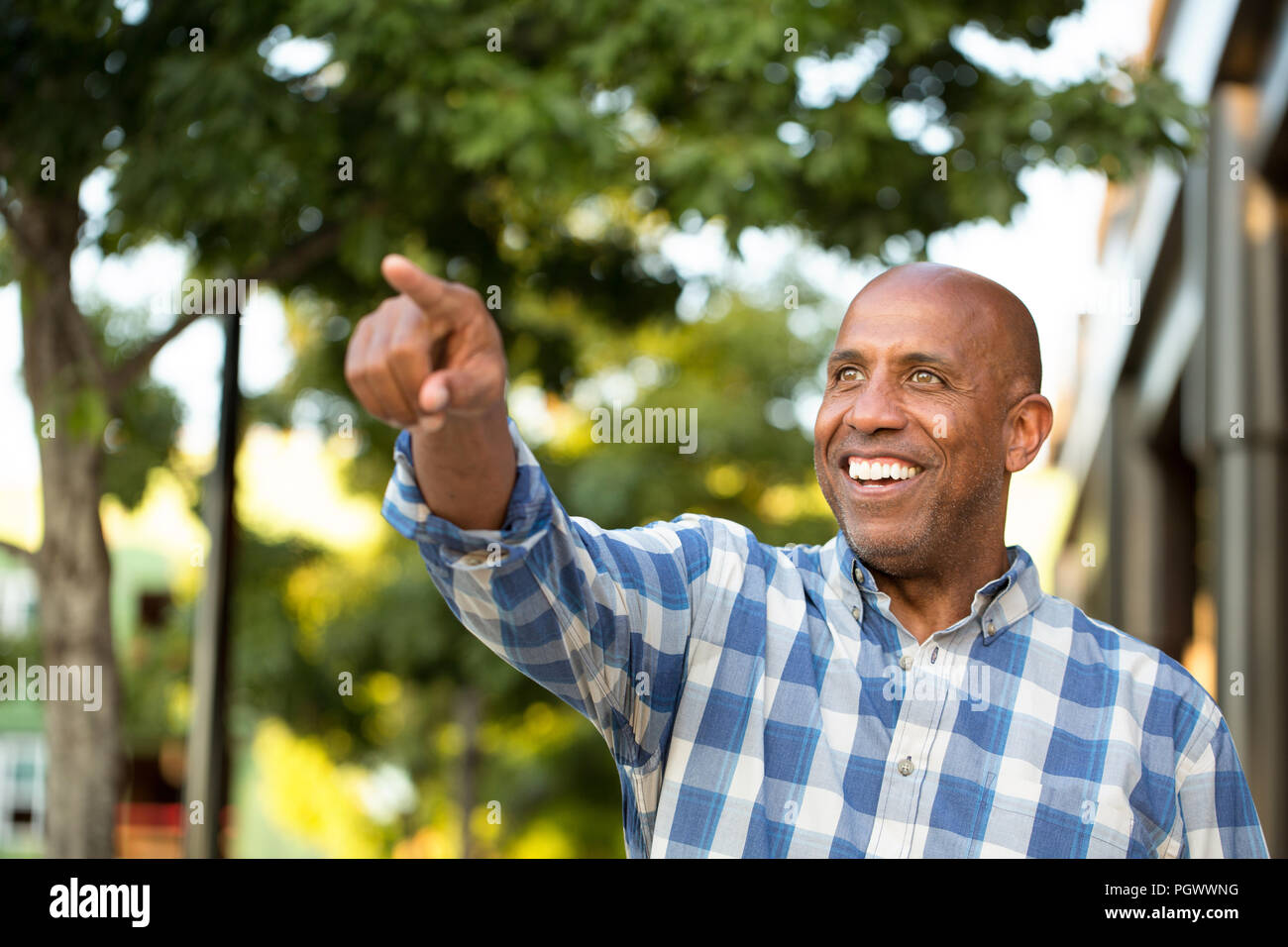 African American man smiling and pointing away from the camera. Stock Photo