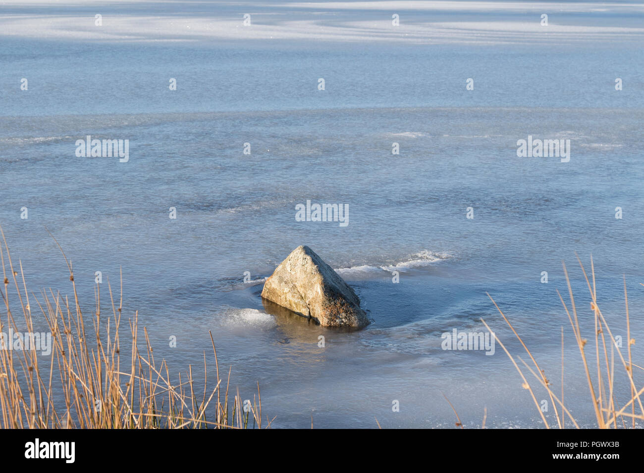 Rock in frozen loch Stock Photo
