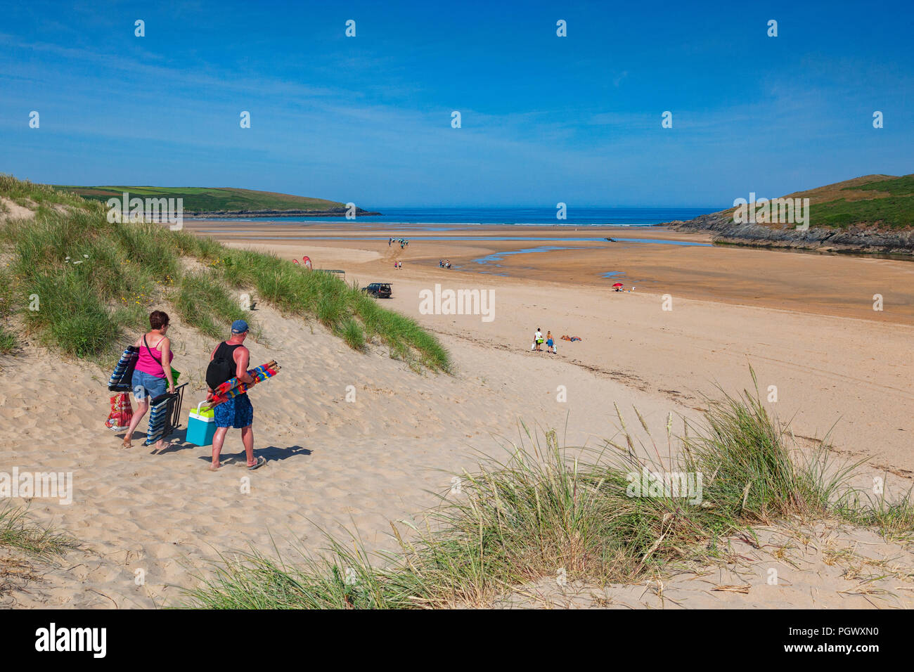 23 June 2018: Crantock Beach, Cornwall, UK - A couple make their way onto the beach on a warm and sunny summer morning. Stock Photo