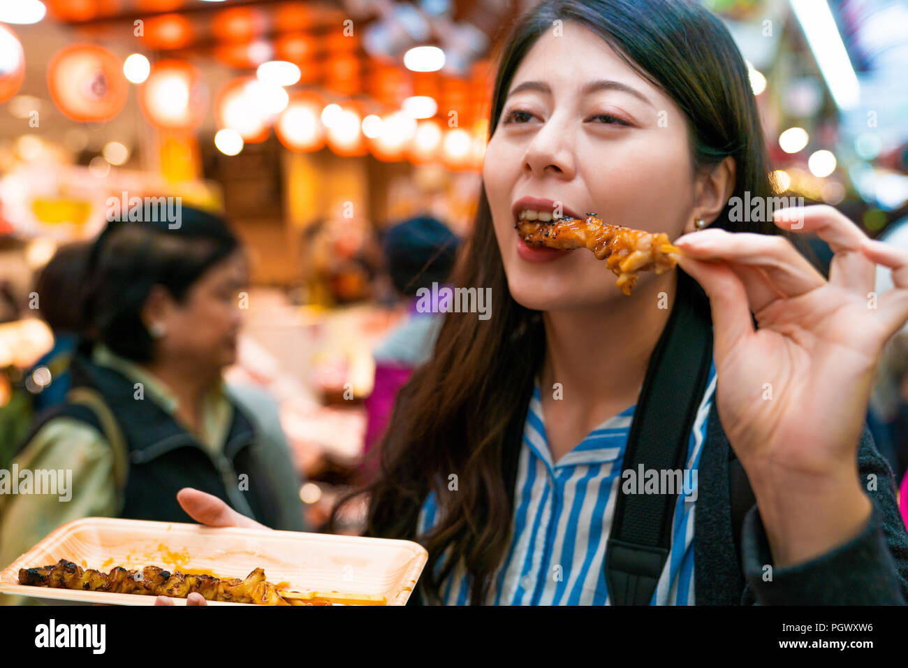 asian visitor eating grilled chicken. by the background of japanese