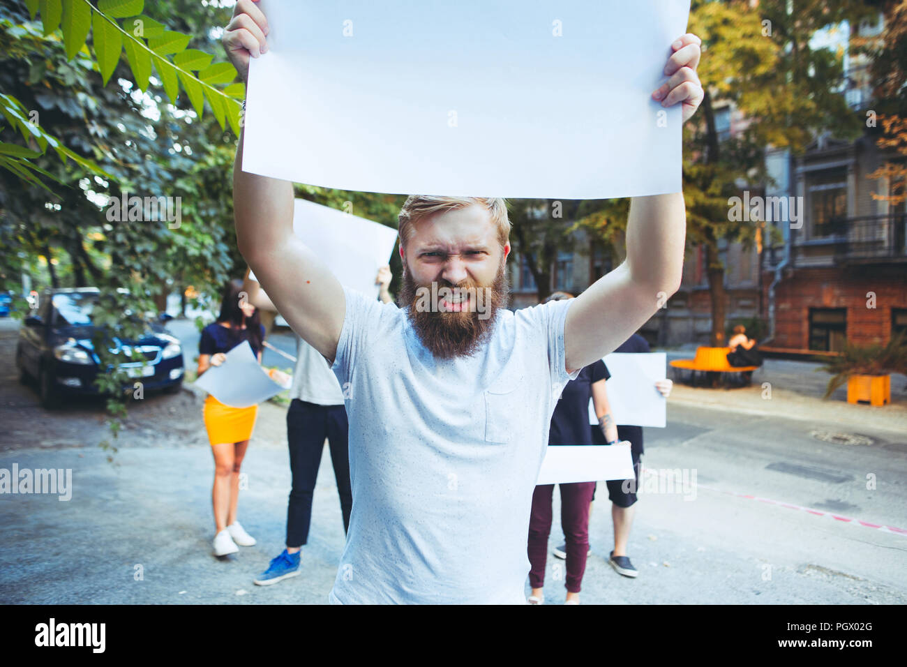 Group of protesting young people outdoors. The protest, people, demonstration, democracy, fight, rights, protesting concept. The caucasian men and womem holding empty posters or banners with copy space Stock Photo