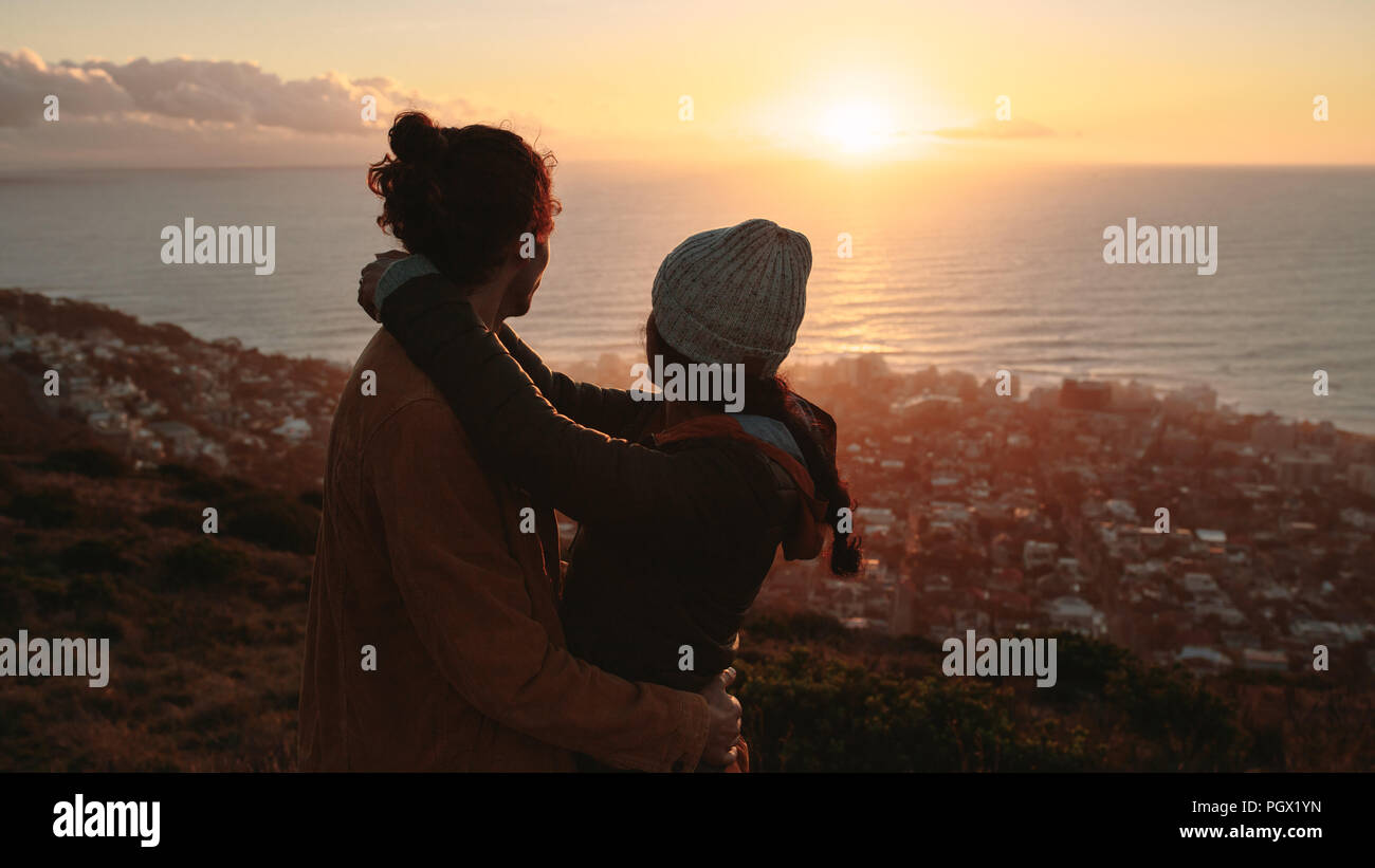 Romantic couple together admiring the sunset over sea from on mountain ...