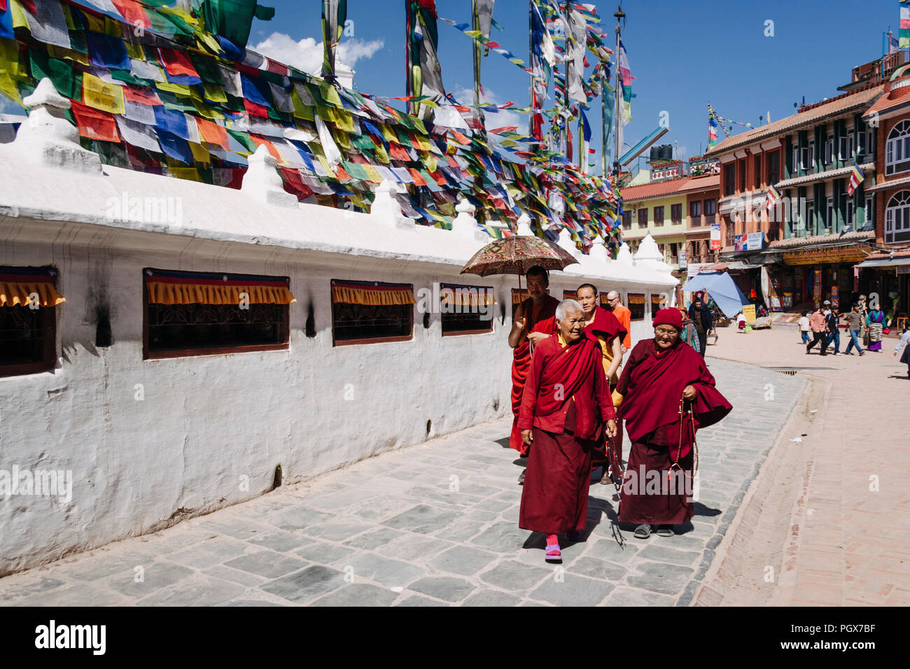 Bodhnath , Kathmandu, Bagmati, Nepal : Buddhist monks and nuns in maroon robes walk around the Great stupa of Bodhnath, the largest in Asia and one of Stock Photo