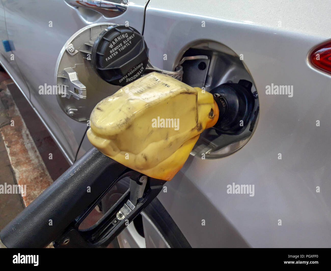 Fuel nozzles adding gasoline fuel in car at a pump gas station Stock