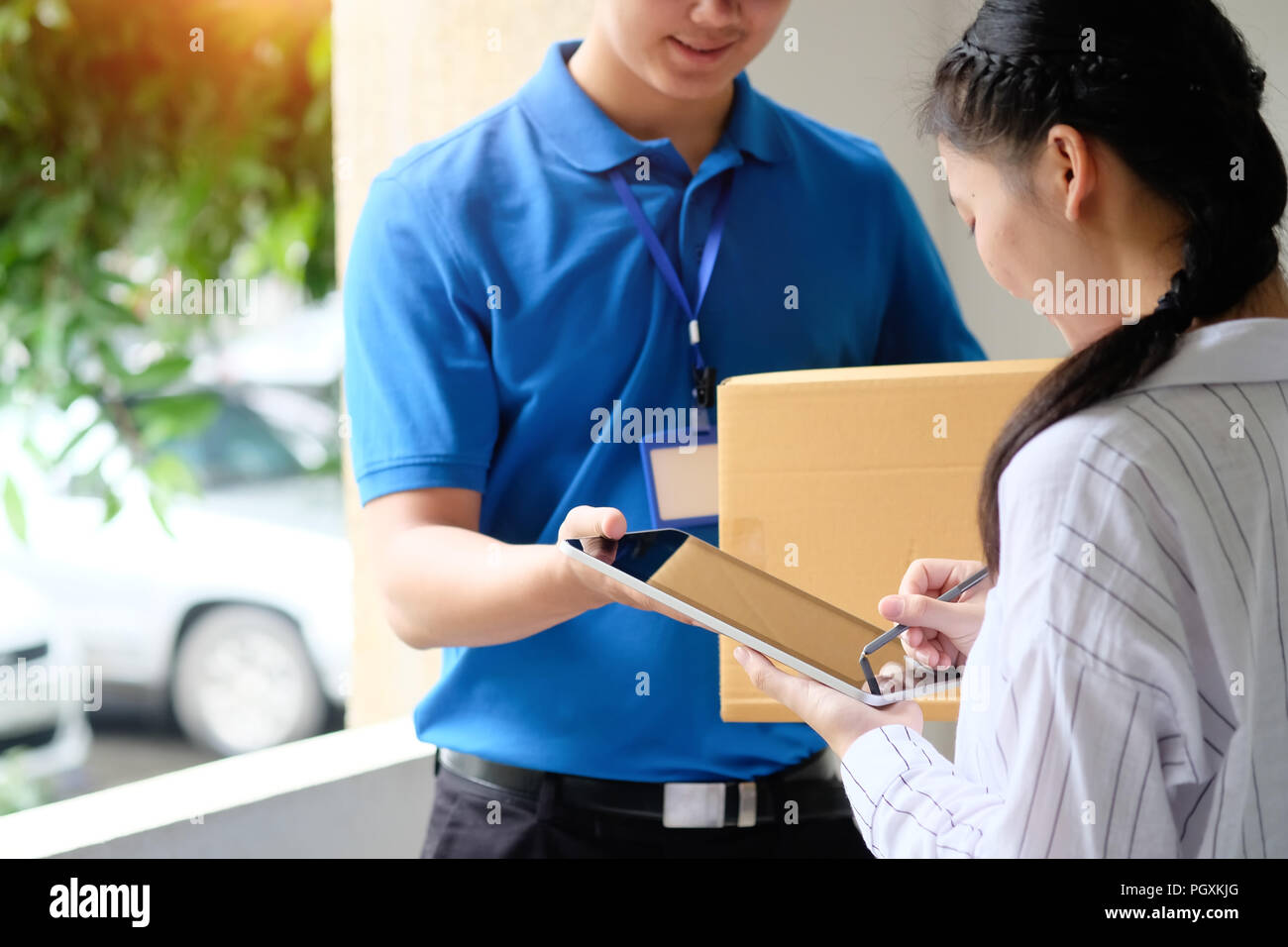 Woman appending signature sign on tablet after accepting receive boxes from delivery man, woman sign on digital tablet, receive delivery concept Stock Photo