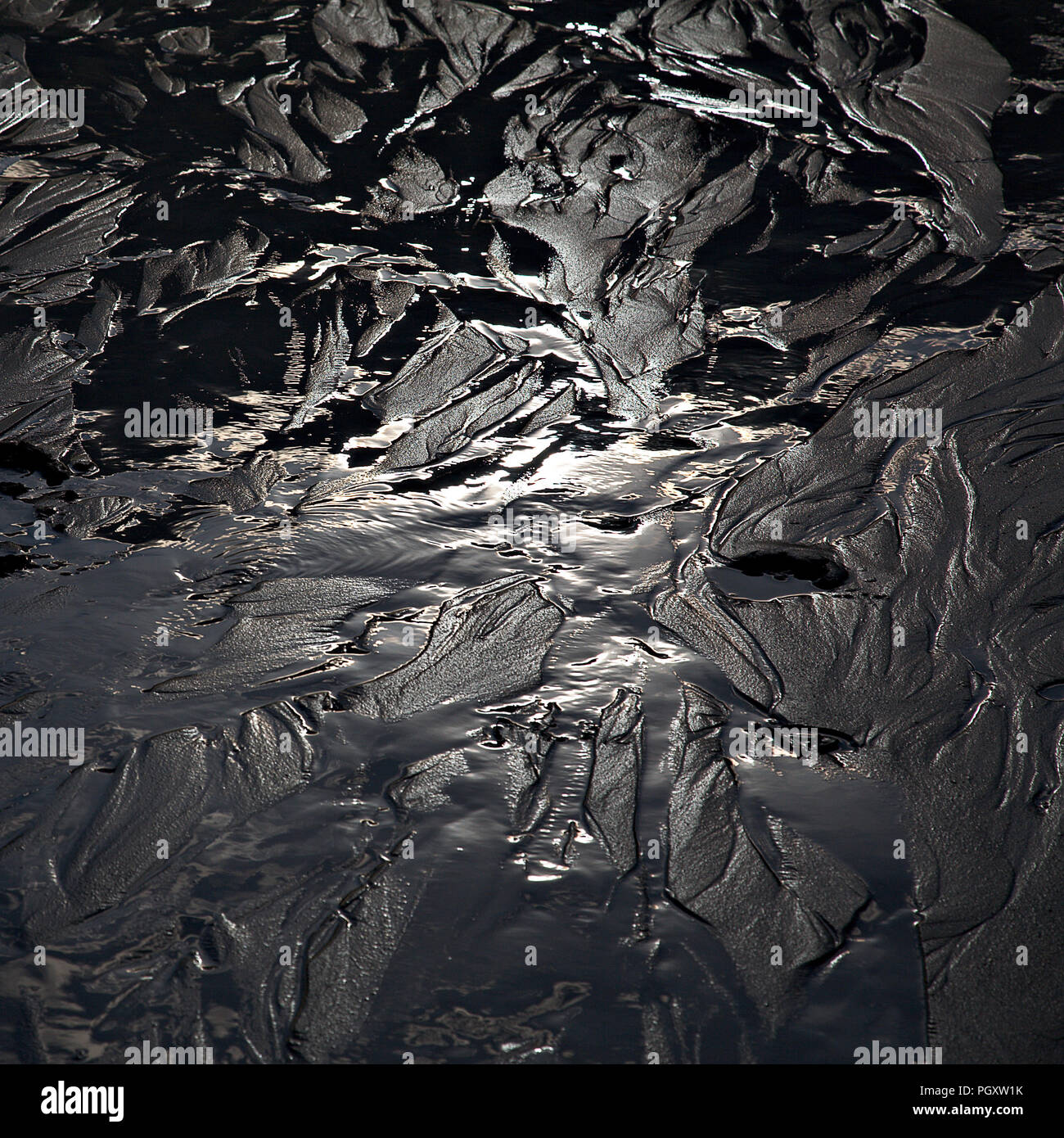 Sunlit patterns in wet sand at low tide on the North Wales coast Stock Photo