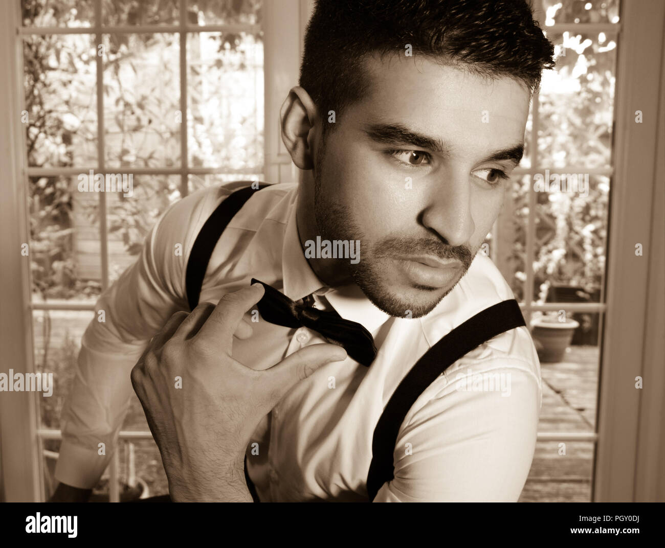 Business, man in tuxedo sits next to window overlooking garden Stock Photo