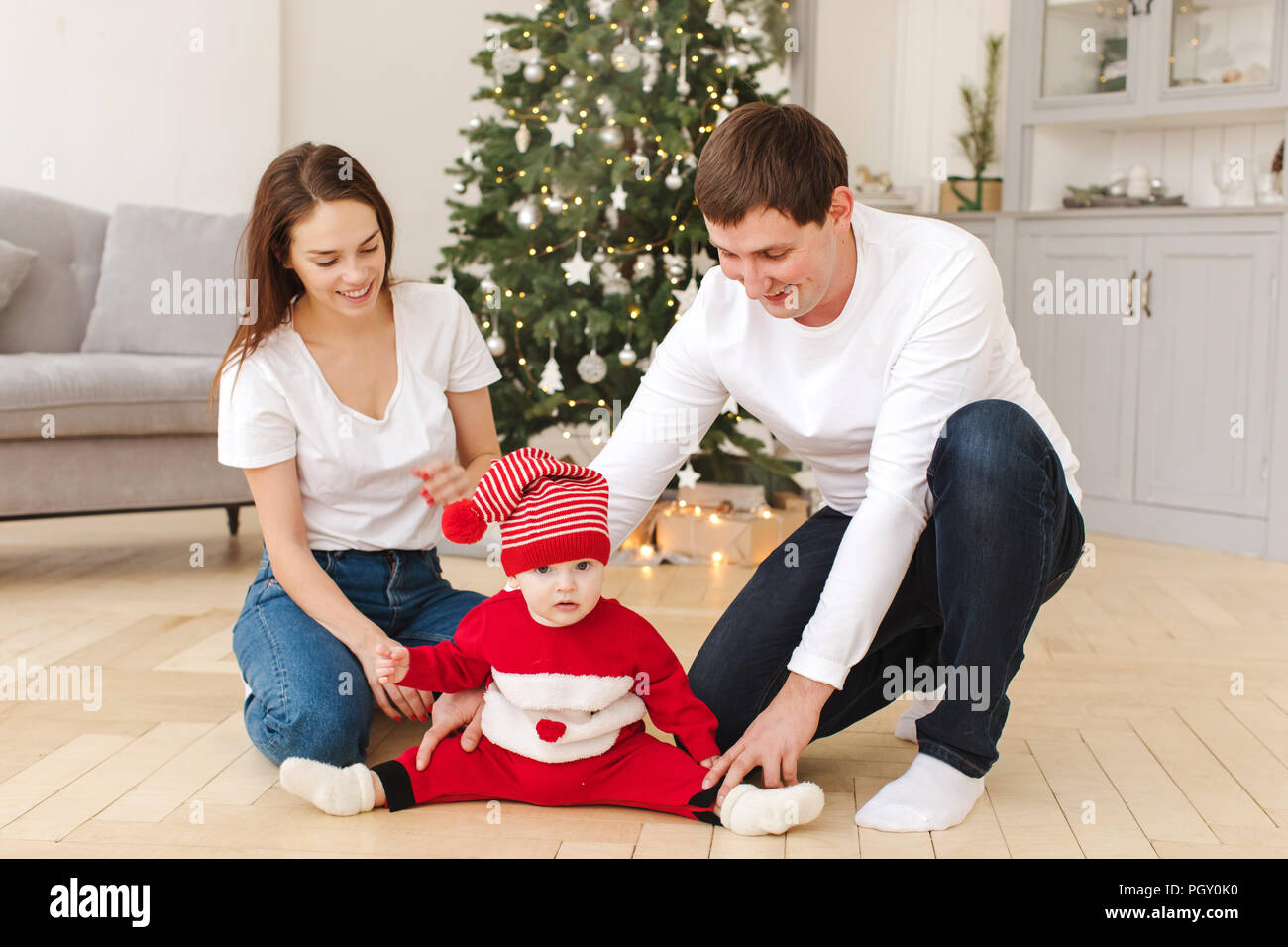 Parents playing with baby near Christmas tree Stock Photo