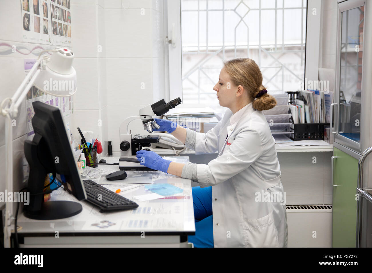 Doctor woman working with a microscope in Laboratory. Female scientist looking through a microscope in lab. Scientist using a microscope in a laboratory. Stock Photo