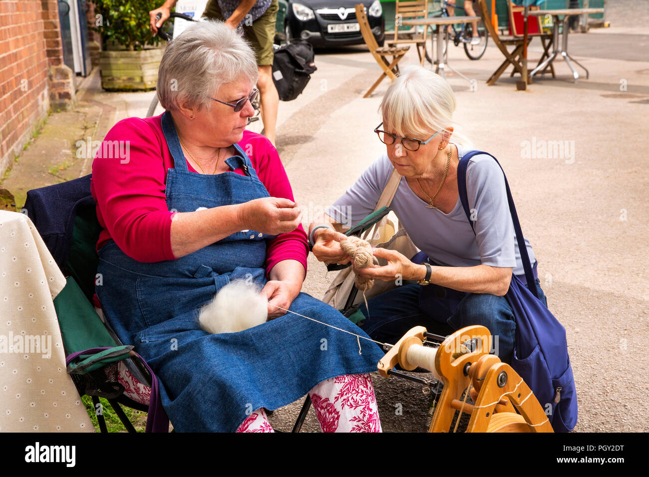 UK, England, Devon, Exeter, Quayside Market knitter Nell Brown explaining spinning to visitor Stock Photo