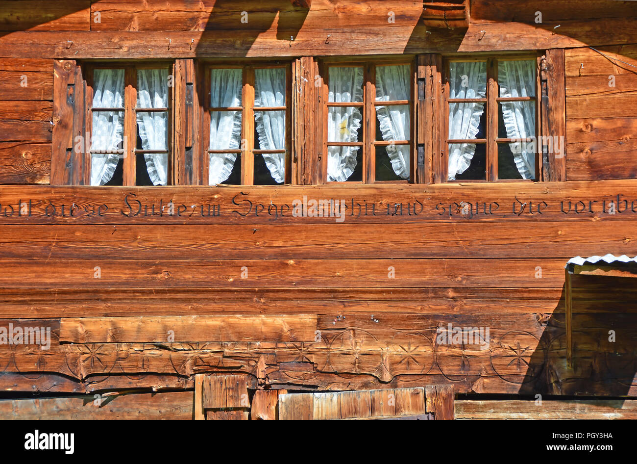 Windows in a traditional Swiss Mountain chalet in a mountain summer hamlet with a dedication in German Stock Photo