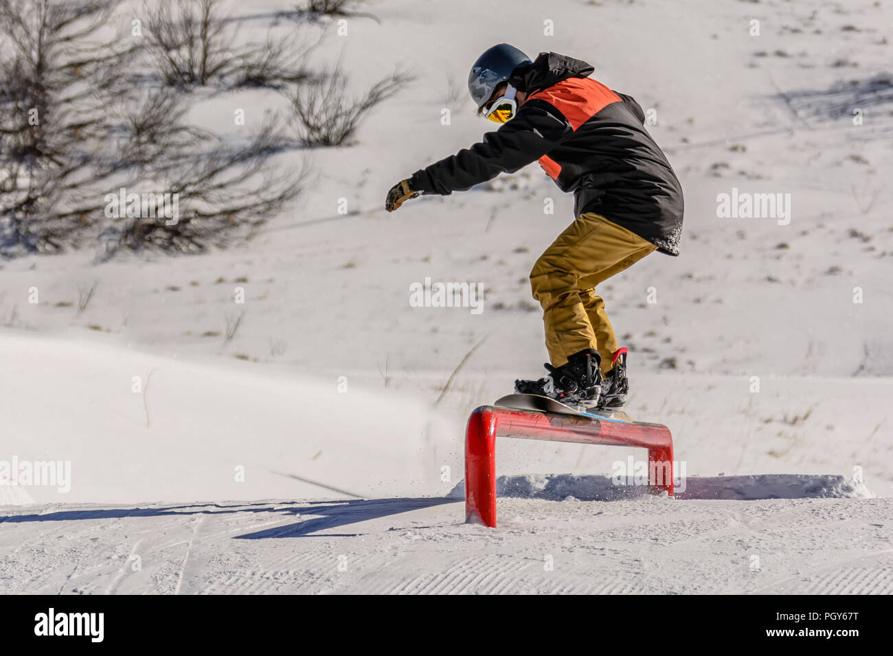 A freestyle snowboarder makes 50-50 slide on a rail Stock Photo - Alamy