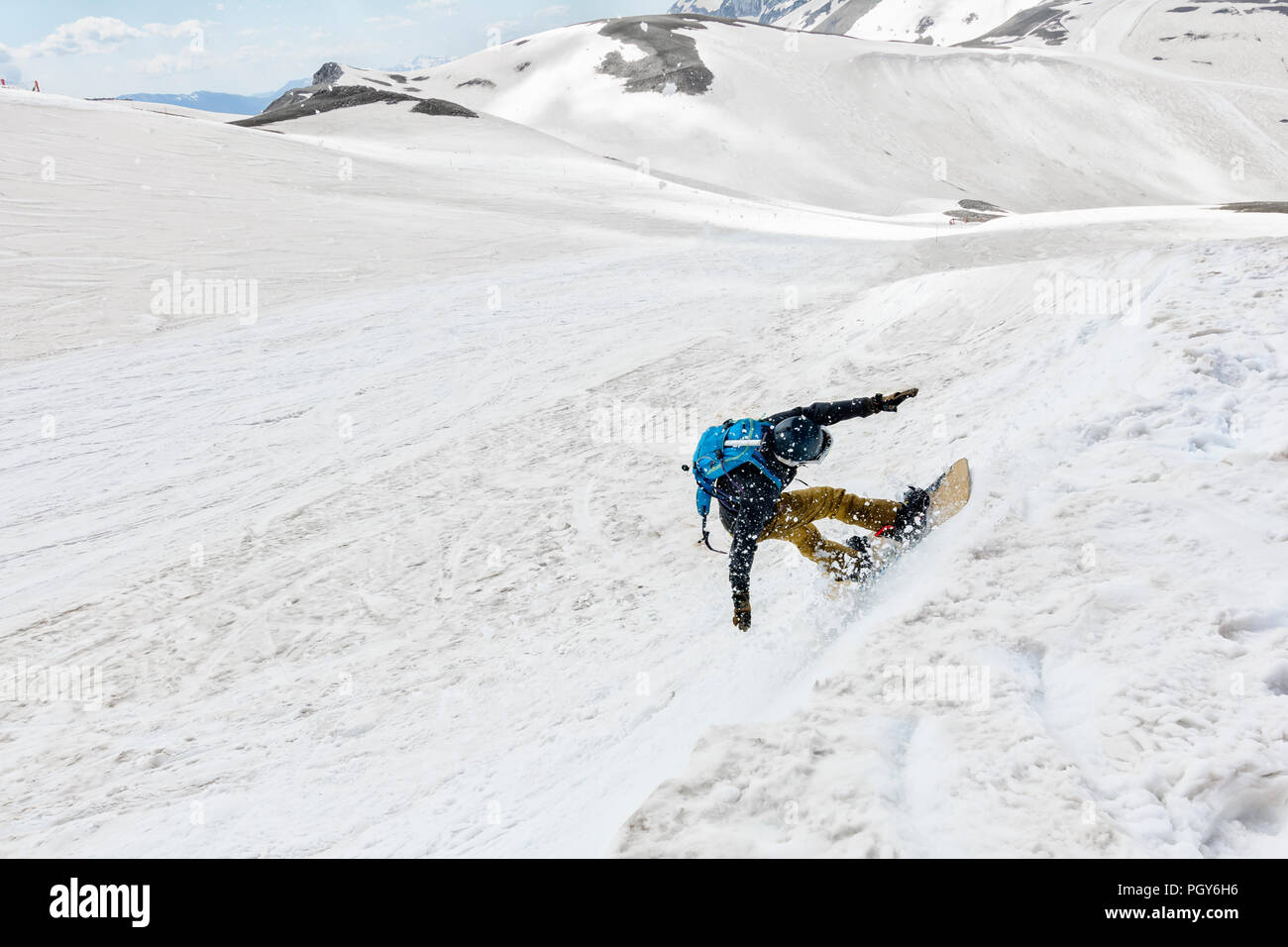 A freeride snowboarder jump from a cliff and makes his trick Stock Photo