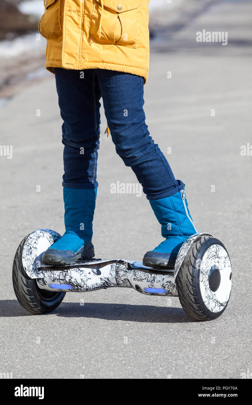 Child standing on groscooter, self-balanced two-wheeled urban mode of transportation, close up view with human feet Stock Photo