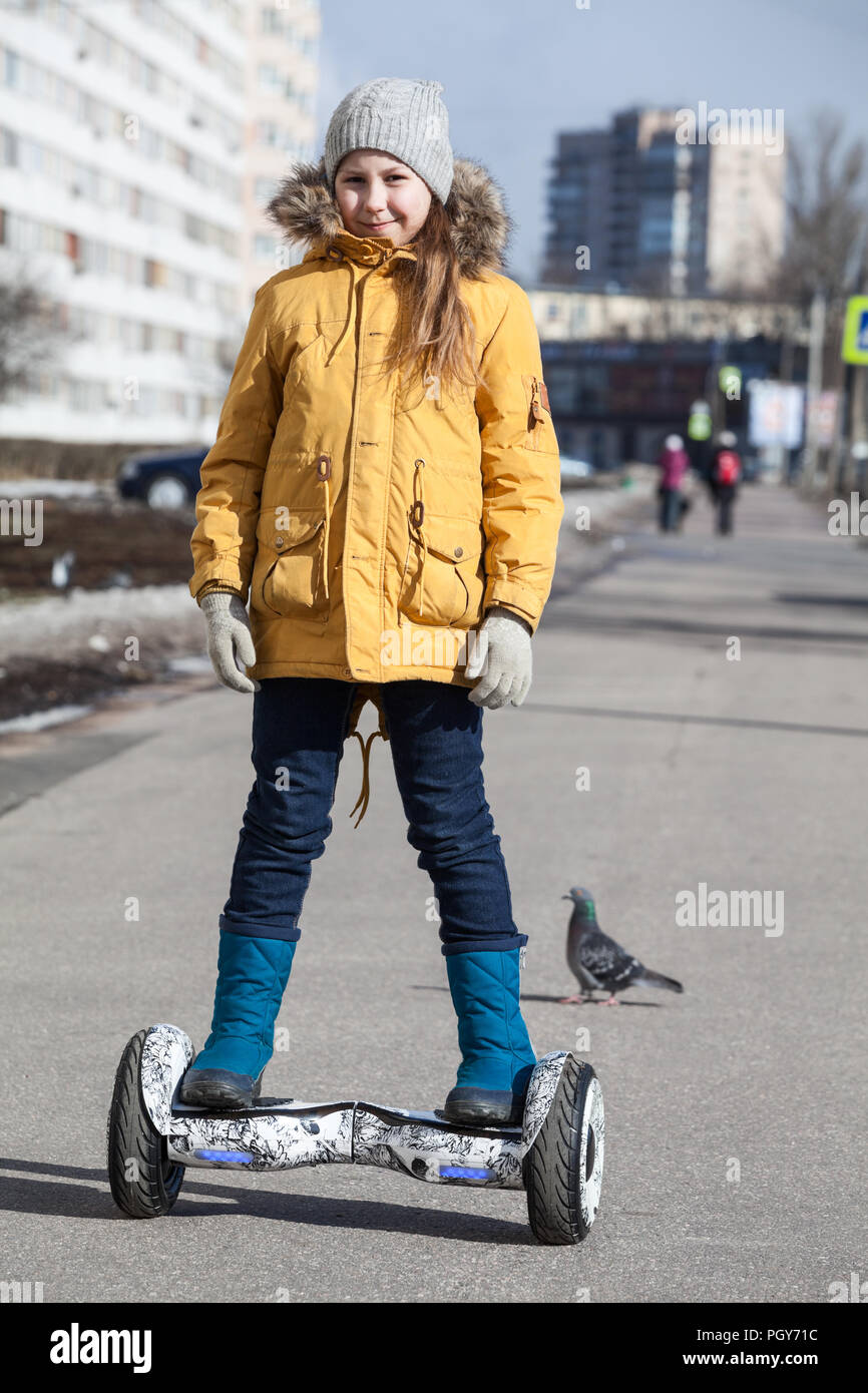 Happy young Caucasian girl driving self balanced vehicle on street pathway Stock Photo