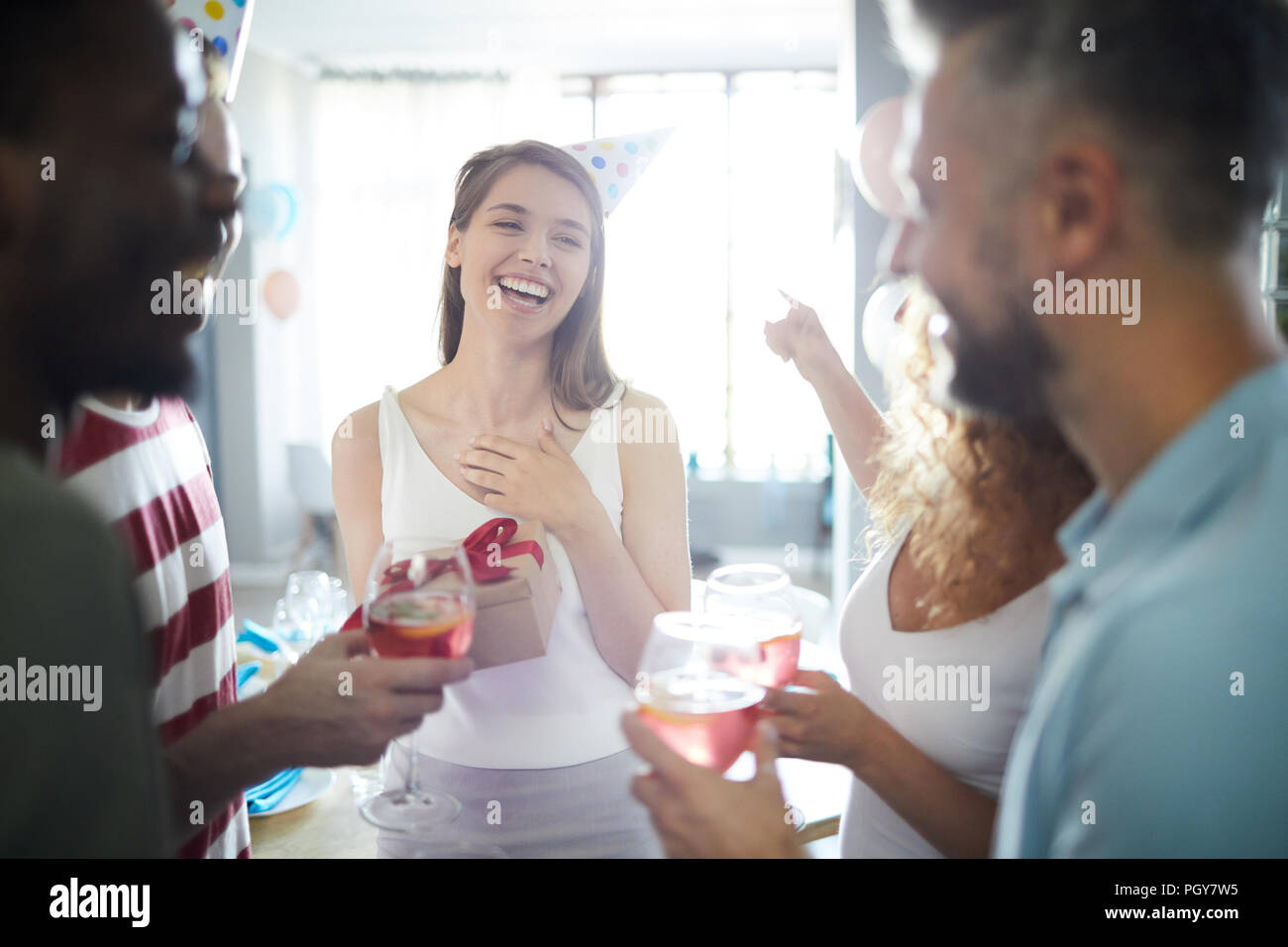 Cheerful girl saying thanks to friends for their present for her birthday at home party Stock Photo
